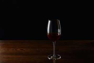 Glass of red wine on wooden surface isolated on black