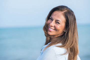 Beautiful middle age hispanic woman standing with smile on face at the ocean. Smiling confident and...