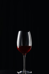 Glass of red wine on dark surface isolated on black