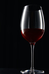 Glass of red wine on dark surface isolated on black