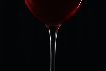 Glass of burgundy red wine isolated on black
