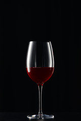 Fototapeta na wymiar Glass with red wine on dark surface isolated on black