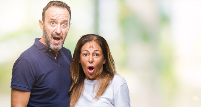 Middle age hispanic casual couple over isolated background afraid and shocked with surprise expression, fear and excited face.