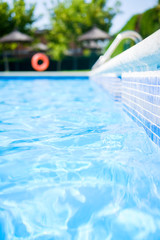 Closeup view of the swimming pool edge with blue water copy space during a sunny summer day