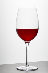 Wine glass with red wine on dark surface on white