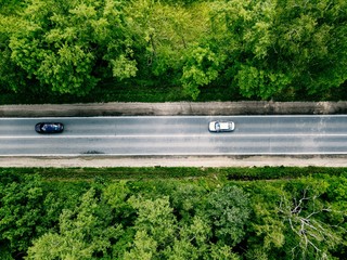 Aerial view of road with cars going through green forest.