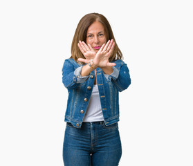 Beautiful middle age woman wearing casual denim jacket over isolated background Rejection expression crossing arms and palms doing negative sign, angry face