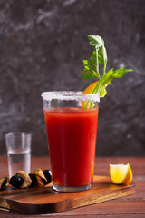 Cocktail Bloody Mary with ice, salt and snacks in glass on a wooden table