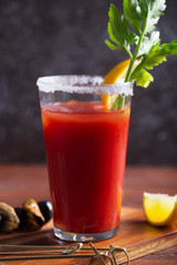 Cocktail Bloody Mary with ice, salt and snacks in glass on a wooden table. Close up shot