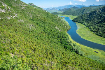 Naklejka na ściany i meble The picturesque meandering river flows among green mountains.