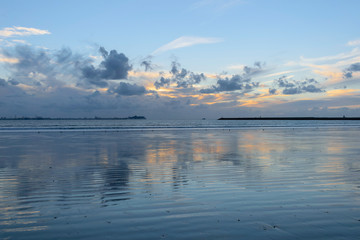 Atardecer en playa mostrando todos los reflejos del cielo sobre la arena mojada