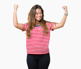Young beautiful brunette woman wearing stripes t-shirt over isolated background showing arms muscles smiling proud. Fitness concept.