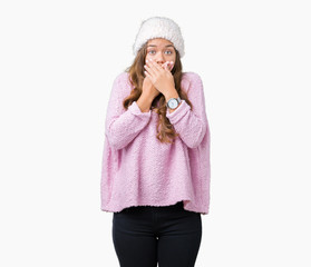 Young beautiful brunette woman wearing sweater and winter hat over isolated background shocked covering mouth with hands for mistake. Secret concept.