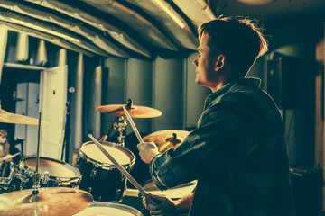 good-looking musician holding drum sticks while playing drums