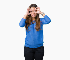 Young beautiful brunette woman wearing blue sweater over isolated background Trying to open eyes with fingers, sleepy and tired for morning fatigue