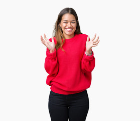 Obraz na płótnie Canvas Young beautiful brunette woman wearing red winter sweater over isolated background celebrating surprised and amazed for success with arms raised and open eyes. Winner concept.