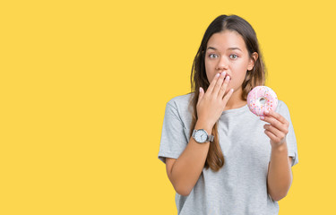 Young beautiful woman eating pink donut over isolated background cover mouth with hand shocked with...