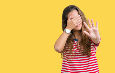 Young beautiful brunette woman wearing stripes t-shirt over isolated background covering eyes with hands and doing stop gesture with sad and fear expression. Embarrassed and negative concept.