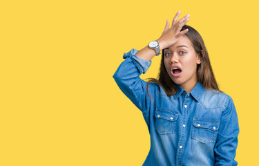 Young beautiful brunette woman wearing blue denim shirt over isolated background surprised with...