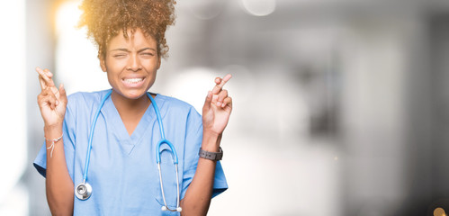 Young african american doctor woman over isolated background smiling crossing fingers with hope and...