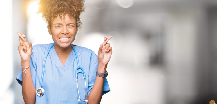 Young african american doctor woman over isolated background smiling crossing fingers with hope and eyes closed. Luck and superstitious concept.