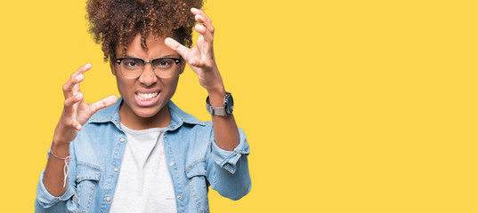 Obraz premium Beautiful young african american woman wearing glasses over isolated background Shouting frustrated with rage, hands trying to strangle, yelling mad