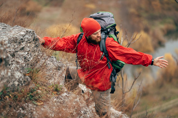 Image of young hiker man hiking in mountains dressed in red clothes exploring new places. Traveler...