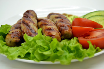 fried sausages and salad on a white plate