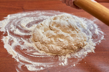 Dough for pizza. Rolling pin and dough on wooden background