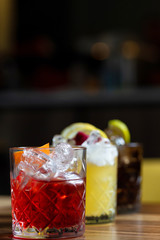 Glasses of cocktails on bar background