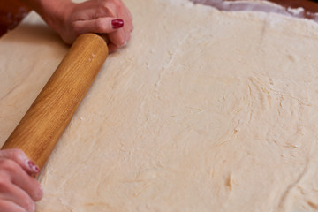 Dough for pizza. Rolling pin and dough on wooden background