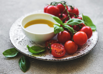 Plate with cherry tomatoes, olive oil and basil