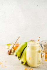 Healthy breakfast, snack. Trendy smoothie cocktail with banana, oatmeal, honey and turmeric. Light concrete background