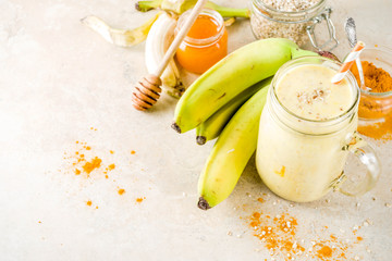 Healthy breakfast, snack. Trendy smoothie cocktail with banana, oatmeal, honey and turmeric. Light concrete background