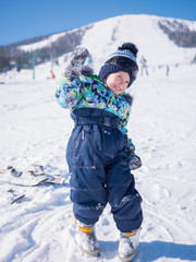 A small child walks in the winter Park. Playing and smiling baby on white fluffy snow. Active rest and games.