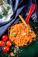 Italian lunch. Homemade spaghetti pasta with classic marinara tomato sauce, spices, garlic, basil. On a dark green concrete table copy space