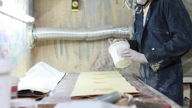 profession, people, carpentry, emotion and people concept - a guy makes glue and glues wooden panels on the manufacture of skateboards. he has protective clothing and mask. 4k