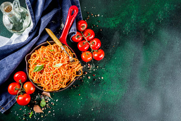 Italian lunch. Homemade spaghetti pasta with classic marinara tomato sauce, spices, garlic, basil. On a dark green concrete table copy space