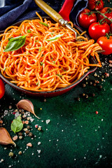 Italian lunch. Homemade spaghetti pasta with classic marinara tomato sauce, spices, garlic, basil. On a dark green concrete table copy space