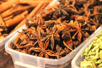 Fragrant cinnamon in plastic containers on a food court. Spices and spices closeup. Anise flowers with and cinnamon sticks.