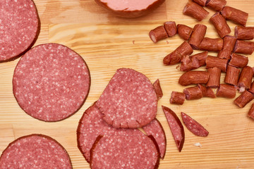 A variety of processed cold meat products, on a wooden cutting board