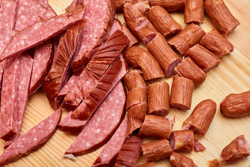 A variety of processed cold meat products, on a wooden cutting board