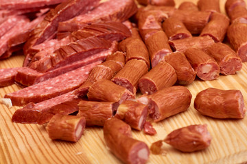 A variety of processed cold meat products, on a wooden cutting board