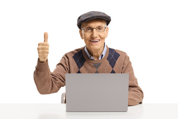 Portrait of a senior man sitting with a laptop and showing thumbs up