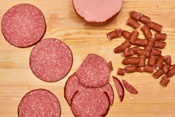 A variety of processed cold meat products, on a wooden cutting board