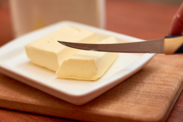 Piece of butter on white plate with knife