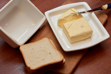 Piece of butter on white plate with knife