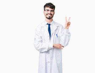 Young professional scientist man wearing white coat over isolated background smiling with happy face winking at the camera doing victory sign. Number two.