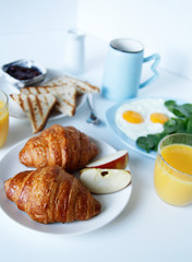 breakfast. side view. light background. scrambled eggs, orange juice, toast, jam, croissants, coffee, milk, morning, close up