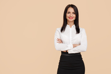 Charming young modern business woman standing over beige background. Success and winner concept.